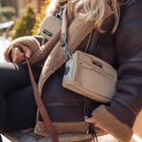 Woman wearing a cream Cocopup London walking bag on the Brown Aviator strap outdoors