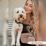 Woman holding a small cream dog while wearing Teddy Rupert walking bag
