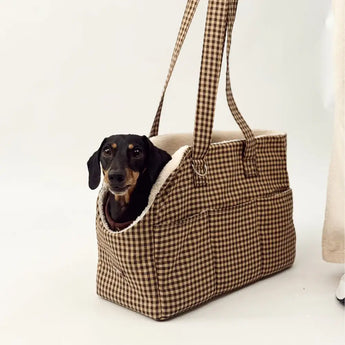 Small black and tan dog sitting in Cotswold Check carrier against a white backdrop
