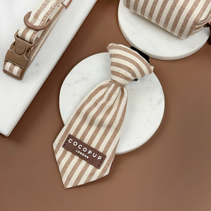 London Linen Stripes Dog Tie angled on a white dish in a brown flat lay, by Cocopup London
