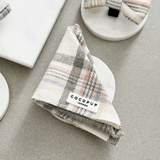 Cocopup London Oxford Plaid Bandana gevouwen op een wit schaaltje in een neutrale flatlay