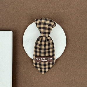 Cotswold Check dog tie displayed straight on a round stone tile