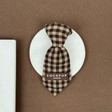 Cotswold Check dog tie displayed straight on a round stone tile