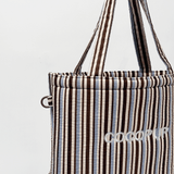 Close-up in studio van de hengsels en het geborduurde Cocopup London-logo op de gestreepte tas