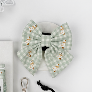 Front flat lay of the green gingham Silly Goose bow tie with embroidered geese