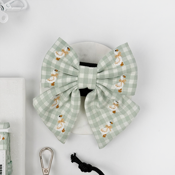 Front flat lay of the green gingham Silly Goose bow tie with embroidered geese