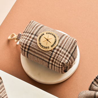 Pup Plaid poop bag holder angled on a round white display
