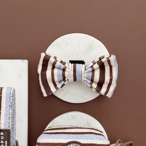 Brown & Blue Stripes dog bow tie displayed front-on on a round stone tile