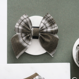 Front view of the Cocopup London Olive Check Sailor Bow Tie on a white dish