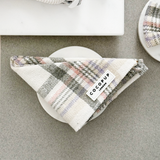 Vooraanzicht van dichtbij van de gevouwen Cocopup London Oxford Plaid Bandana in een neutrale flatlay met accessoires