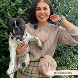 Woman outdoors holding a black and white French bulldog while wearing Teddy Rupert bag