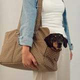 Woman carrying a small black and tan dog in the Cotswold Check carrier at her side