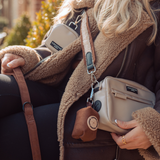 Close view of woman wearing Brown Aviator strap with cream walking bag and brown treat pouch