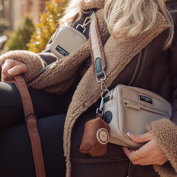 Close view of woman wearing Brown Aviator strap with cream walking bag and brown treat pouch