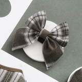Cocopup London Olive Check Sailor Bow Tie angled on a white dish in a green flat lay