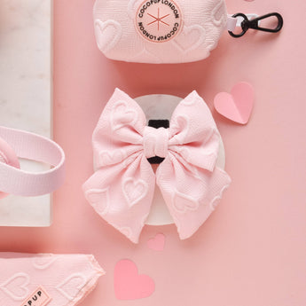Front view of the Cocopup London Baby Pink Heart Luxe Sailor Bow Tie in a pink flat lay